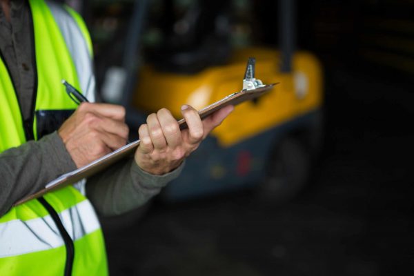 Male worker writing on clipboard taking risk assessment